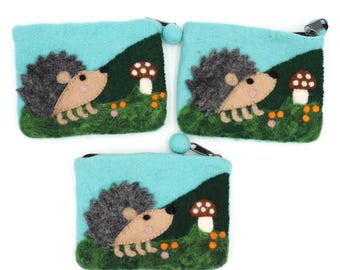 Può includere: Tre portamonete in feltro con un design a riccio stravagante. Ogni portamonete presenta uno sfondo azzurro, una collina verde scuro e un affascinante riccio con un fungo e fiori. Chiusura con cerniera e un piccolo pompon blu.