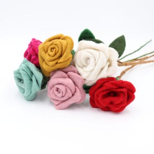 May include: A bouquet of handmade felt roses in various colors, including pink, red, yellow, white, and teal. The flowers have green felt leaves and brown stems, perfect for crafting or home decor.