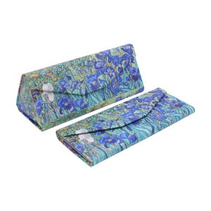May include: Two eyeglass cases with a floral design. The cases are covered in a print of blue irises and other flowers on a green background. One case is triangular and closed, while the other is rectangular and open.