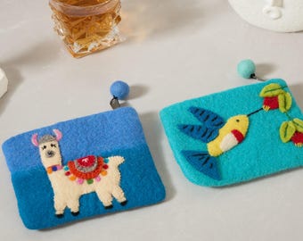 Può includere: Due pochette in feltro con sfondi blu e turchese. Una presenta un lama con una sella colorata, l'altra un colibrì con corpo giallo e ali blu. Ognuna ha un pompon blu attaccato.