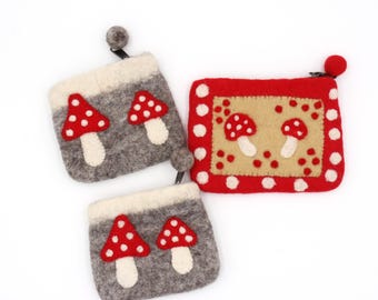Può includere: Tre pochette in feltro con disegni di funghi. Due pochette grigie hanno applicazioni di funghi rossi e bianchi. La terza pochette è rossa con un centro beige e applicazioni di funghi. Le pochette hanno cerniere e piccoli tiranti a sfera.