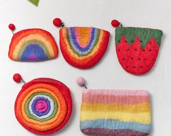 Può includere: Cinque portamonete colorati in feltro. I portamonete hanno la forma di un arcobaleno, una fragola e una spirale. Ogni portamonete ha una cerniera e una pallina attaccata. I portamonete sono fatti di lana.