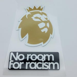 May include: A gold and white Premier League lion logo sticker with a crown. Below is a black rectangle with the words "No room for racism" in white. The sticker is on a clear backing.