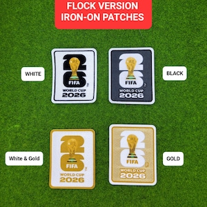 May include: Four iron-on patches in white, black, white & gold, and gold. Each patch features the FIFA World Cup 2026 logo with a gold trophy. The patches are rectangular with rounded corners, set against a green background.