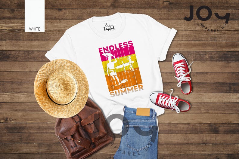 May include: White t-shirt with "ENDLESS SUMMER" graphic, straw hat, brown backpack, blue jeans, and red sneakers. The shirt features a colorful design of a person with a surfboard. The items are arranged on a wooden surface.