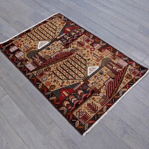 Pu&ograve; includere: Un tappeto tradizionale con un motivo geometrico in tonalit&agrave; di rosso, marrone e beige. Il tappeto presenta un motivo ripetitivo di alberi e case stilizzate.