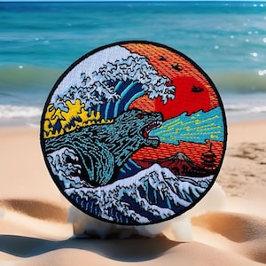 May include: A circular embroidered patch featuring a Godzilla-like monster breathing fire, emerging from a large wave with a red sun and Mount Fuji in the background.