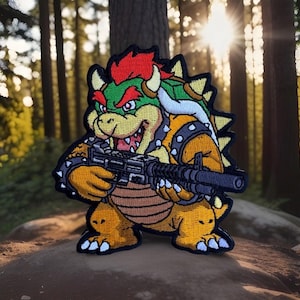 May include: An embroidered patch featuring a cartoon character with a green shell, yellow skin, red hair, and horns, holding a black rifle. The character has a spiked collar and wristbands, with a brown belly and sharp teeth visible in a grin.
