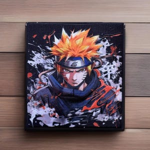 May include: A black and white patch with a colorful image of a character from the anime Naruto. The character has orange hair, a blue headband with a white swirl, and a blue and black outfit. The background is a black and white splatter pattern.