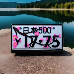 May include: White license plate with black text and a pink cherry blossom design. The text reads "日本 500" and "Y 17-75".