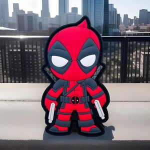 May include: A red and black cartoon character with a mask and two pistols. The character is standing on a gray surface.