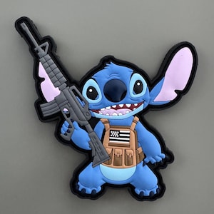 May include: A blue cartoon character with large ears, holding a black rifle and wearing a brown tactical vest with an American flag patch.