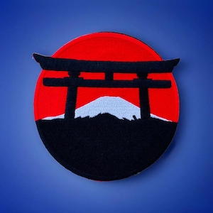 May include: A red and black embroidered patch with a white mountain and a black torii gate in front of it. The patch is circular and has a red background.