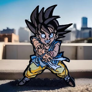 May include: Embroidered patch of a cartoon character with spiky brown hair, wearing a blue and yellow outfit, with a white belt and a pink bracelet. The character is in a fighting pose with their fists clenched.