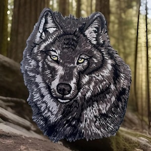 May include: A close-up of a gray embroidered wolf head patch. The wolf has a serious expression with piercing yellow eyes.