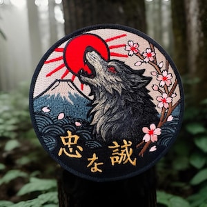May include: Embroidered patch featuring a howling wolf with red eyes against a backdrop of a red sun and Mount Fuji. Cherry blossoms and Japanese text are also included in the design. The patch has a black border.