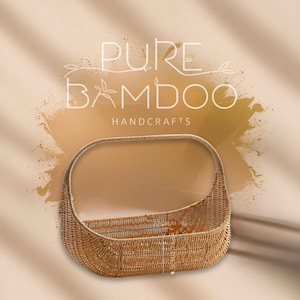 May include: A woven bamboo basket with a curved handle. The basket is light brown and has a rectangular shape. The text "PURE BAMBOO HANDCRAFTS" is displayed in white above the basket. The basket measures 22cm x 14cm x 6cm.