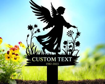 May include: Black metal silhouette of an angel with wings, holding a flower, standing in a field of flowers. The angel is holding a sign with the text "CUSTOM TEXT 1982-2023".