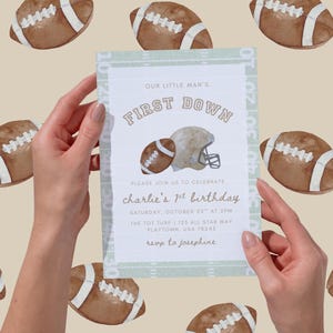 May include: An invitation with the text "OUR LITTLE MAN'S FIRST DOWN" and "charlie's 1st birthday". The invitation features a football and helmet illustration. The background has a pattern of footballs. The invitation is light green and white.
