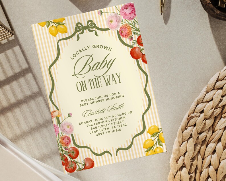 May include: Baby shower invitation with a cream background and vertical yellow stripes. The text reads "Locally Grown Baby On The Way." Floral and fruit illustrations, including lemons, tomatoes, and roses, decorate the border. The invitation includes the date, time, and location.