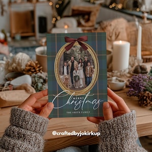 May include: A Christmas card with a family photo inside an oval frame, adorned with a burgundy bow. The card features a green and blue plaid pattern and the words "Merry Christmas" in elegant script. The family name is also included.