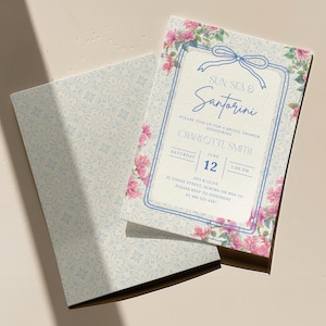Könnte beinhalten: Eine Einladung zur Brautparty mit floralem Design. Die Einladung zeigt den Text "Sun Sea & Santorini" und Details zur Veranstaltung. Die Einladung ist von rosa Blumen und einem blauen Rahmen umgeben. Ein Umschlag mit passendem floralem Muster ist ebenfalls vorhanden.