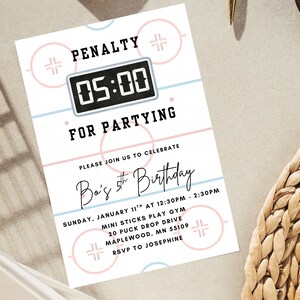 May include: A white invitation card with a hockey theme. The card features a hockey rink design with pink and blue accents. Text includes "PENALTY", "05:00", "FOR PARTYING", and "Ba's 5th Birthday". Party details are also included.