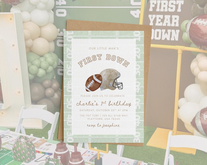 May include: A football-themed invitation card with a brown envelope. The card features a football and helmet illustration, with the text "OUR LITTLE MAN'S FIRST DOWN" and details for a first birthday celebration.