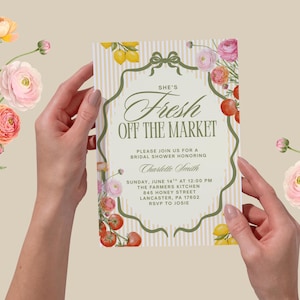 May include: A bridal shower invitation with the text "She's Fresh Off The Market" in elegant script. The invitation is held by hands and decorated with floral and fruit illustrations, including lemons, tomatoes, and roses.