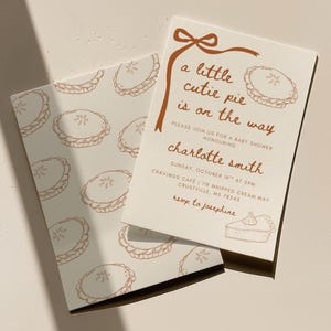May include: Baby shower invitation with a pie theme. The invitation features the text "a little cutie pie is on the way" in brown script. The invitation also includes the name "Charlotte Smith" and event details.