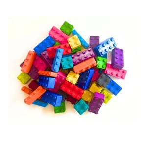 May include: A collection of rectangular and square plastic building blocks in a variety of vibrant colors including red, blue, green, yellow, orange, purple, and pink. Each block features a grid of circular studs on the top surface for connecting.