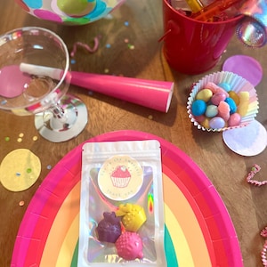 May include: A clear resealable pouch containing three small cupcake-shaped wax melts in purple, yellow, and pink. The pouch features a circular sticker with a pink cupcake illustration and the text You're the sweetest Thank you.