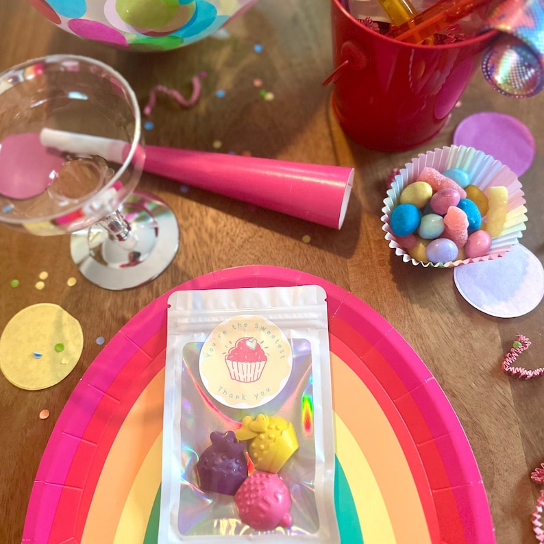 May include: A clear resealable pouch containing three small cupcake-shaped wax melts in purple, yellow, and pink. The pouch features a circular sticker with a pink cupcake illustration and the text You're the sweetest Thank you.