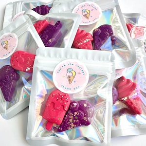 May include: Multiple holographic pouches containing wax melts shaped like ice cream cones and popsicles in shades of pink and purple with glitter accents. Each pouch features a circular sticker with an ice cream illustration and the text You're the coolest Thank you.