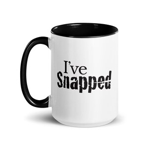 May include: White ceramic coffee mug with a black rim and handle. The mug has the text "I've Snapped" printed in black.