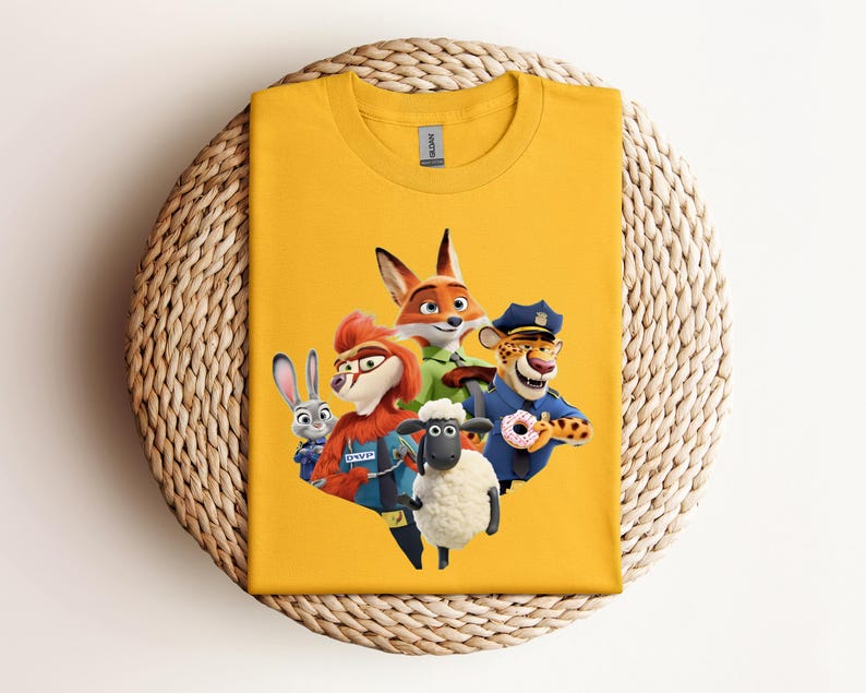 May include: Mustard yellow t-shirt featuring a colorful graphic of characters from the animated movie Zootopia. The design includes a fox, a rabbit, a sheep, a cheetah, and a character wearing a police hat. The shirt is displayed on a woven surface.