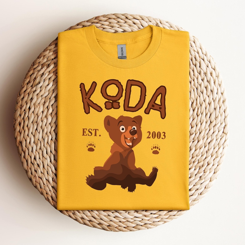 May include: Yellow t-shirt with a brown cartoon bear and the text "KODA EST. 2003".
