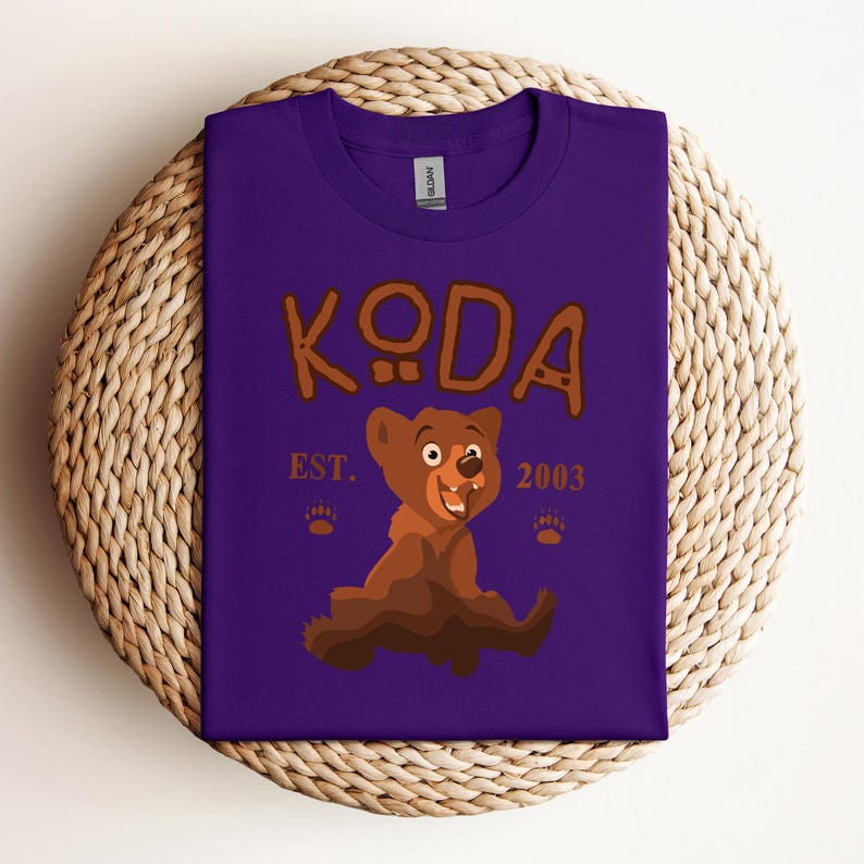 May include: Purple t-shirt with a brown cartoon bear and the text "KODA EST. 2003".