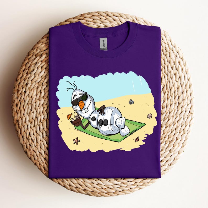 Op de afbeelding: Paars T-shirt met een cartoon afbeelding van Olaf uit Frozen, die een zonnebril draagt en ontspant op een strandhanddoek met een tropisch drankje.