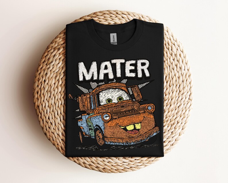 May include: Black t-shirt featuring a distressed graphic of Mater from the movie Cars. The word "MATER" is printed above the character in a bold, white font. The graphic includes shades of brown, blue, and orange.