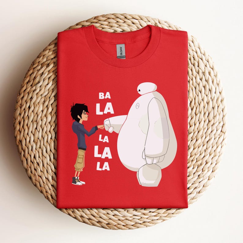 K&ouml;nnte beinhalten: Rotes T-Shirt mit einem wei&szlig;en Roboter und einer Comicfigur mit dem Text "BA LA LA LA LA" auf der Vorderseite.