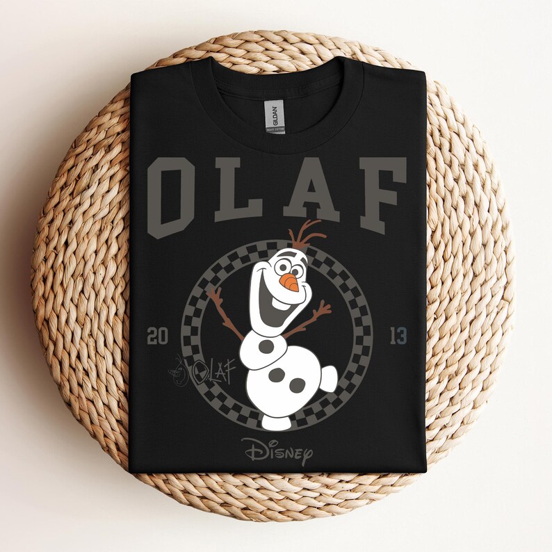 Może przedstawiać: Czarny T-shirt z białym nadrukiem Olafa z Krainy Lodu. Nadruk przedstawia Olafa w kwadratowym k&oacute;łku z tekstem "Olaf" nad nim i "Disney" pod nim.