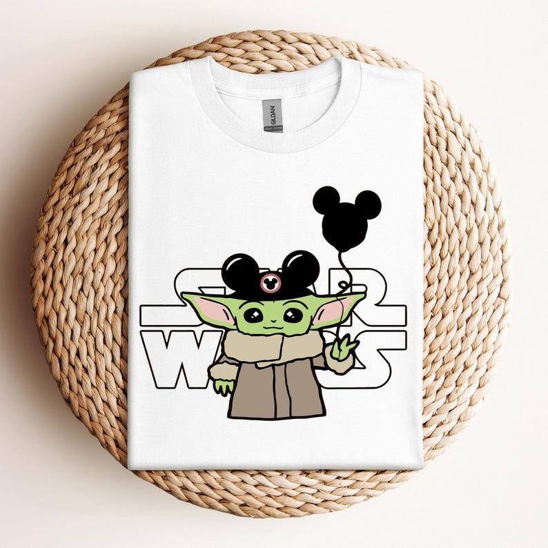 Puede incluir: Camiseta blanca con un personaje alien&iacute;gena verde que lleva un sombrero de Mickey Mouse y sostiene un globo de Mickey Mouse. El texto "Star Wars" est&aacute; impreso en la camiseta.