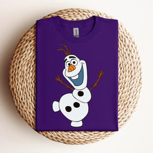 Pode incluir: Camiseta roxa com uma imagem de desenho animado de Olaf, o boneco de neve de Frozen, com um grande sorriso e os bra&ccedil;os estendidos.