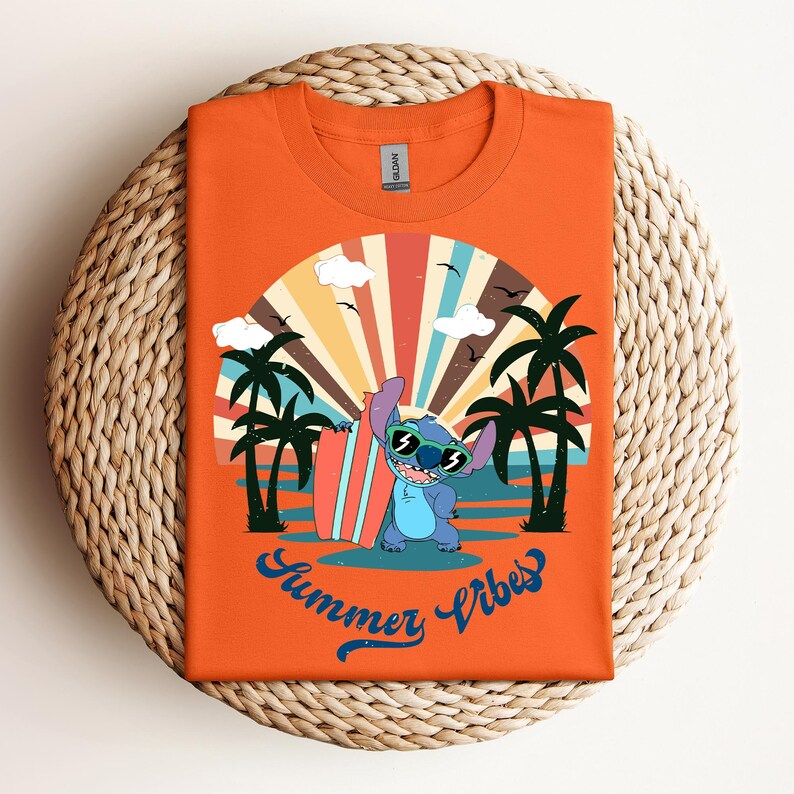 May include: Orange t-shirt with a cartoon character wearing sunglasses and holding a surfboard, set against a beach scene with palm trees and a sunset. The text "Summer Vibes" is written in blue script.