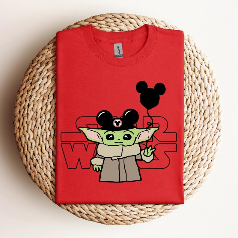 Puede incluir: Camiseta roja con un personaje verde que lleva un sombrero de Mickey Mouse y sostiene un globo de Mickey Mouse. El texto "STAR WARS" est&aacute; impreso en la camiseta.