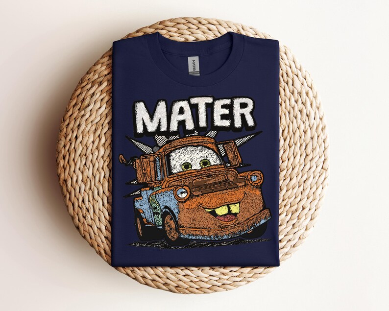 May include: Navy blue t-shirt featuring a graphic of Mater from the movie Cars. The word "MATER" is printed above the character in a white, distressed font. The cartoon Mater is brown, blue, and orange.