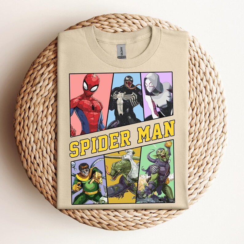 Pode incluir: Uma camiseta bege com um gr&aacute;fico vibrante do Homem-Aranha e outros personagens. O design inclui Homem-Aranha, Venom, Spider-Gwen, Doutor Octopus, Lagarto e Duende Verde. As palavras "SPIDER MAN" est&atilde;o em letras amarelas.
