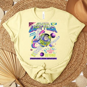 Puede incluir: Camiseta amarillo claro con un dise&ntilde;o de Buzz Lightyear. El dise&ntilde;o incluye las palabras "Buzz Lightyear" en una fuente colorida, con la frase "&iexcl;Al infinito y m&aacute;s all&aacute;!". La camiseta est&aacute; hecha de material suave.
