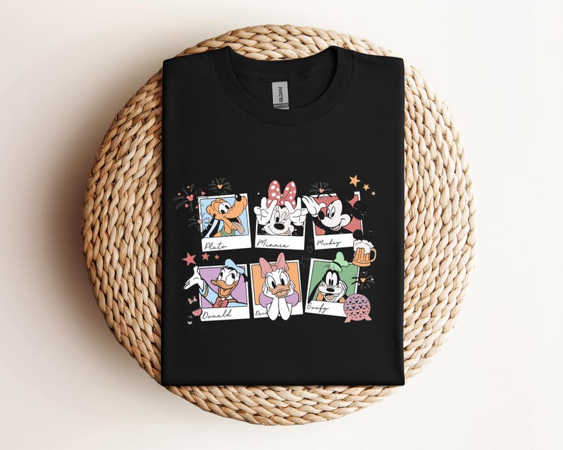 May include: A black crew neck t-shirt featuring a graphic print of six polaroid-style frames. Each frame contains a Disney character: Pluto, Minnie Mouse, Mickey Mouse, Donald Duck, Daisy Duck, and Goofy, with their names written below each image.